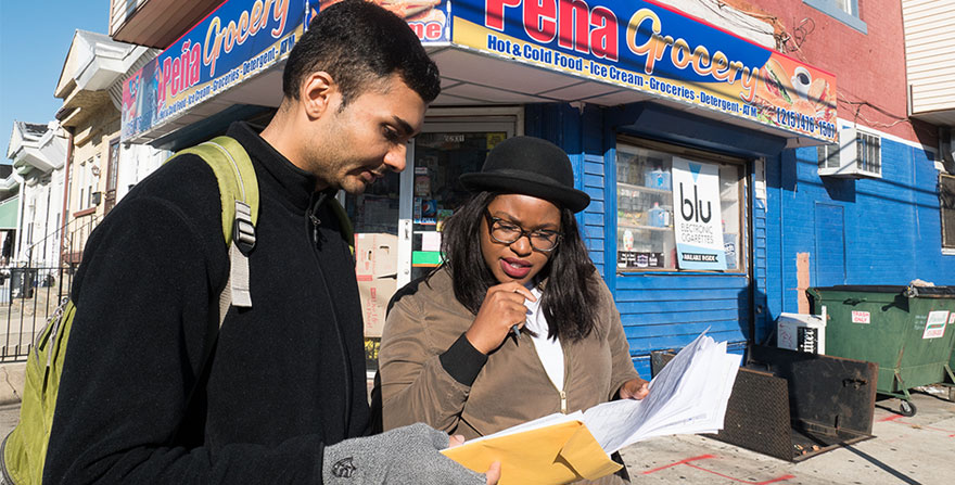 Young man and woman examining their notes, in front of a corner store